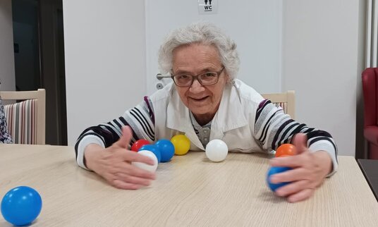 Bewohnerin spielt am Tisch mit Bällen 